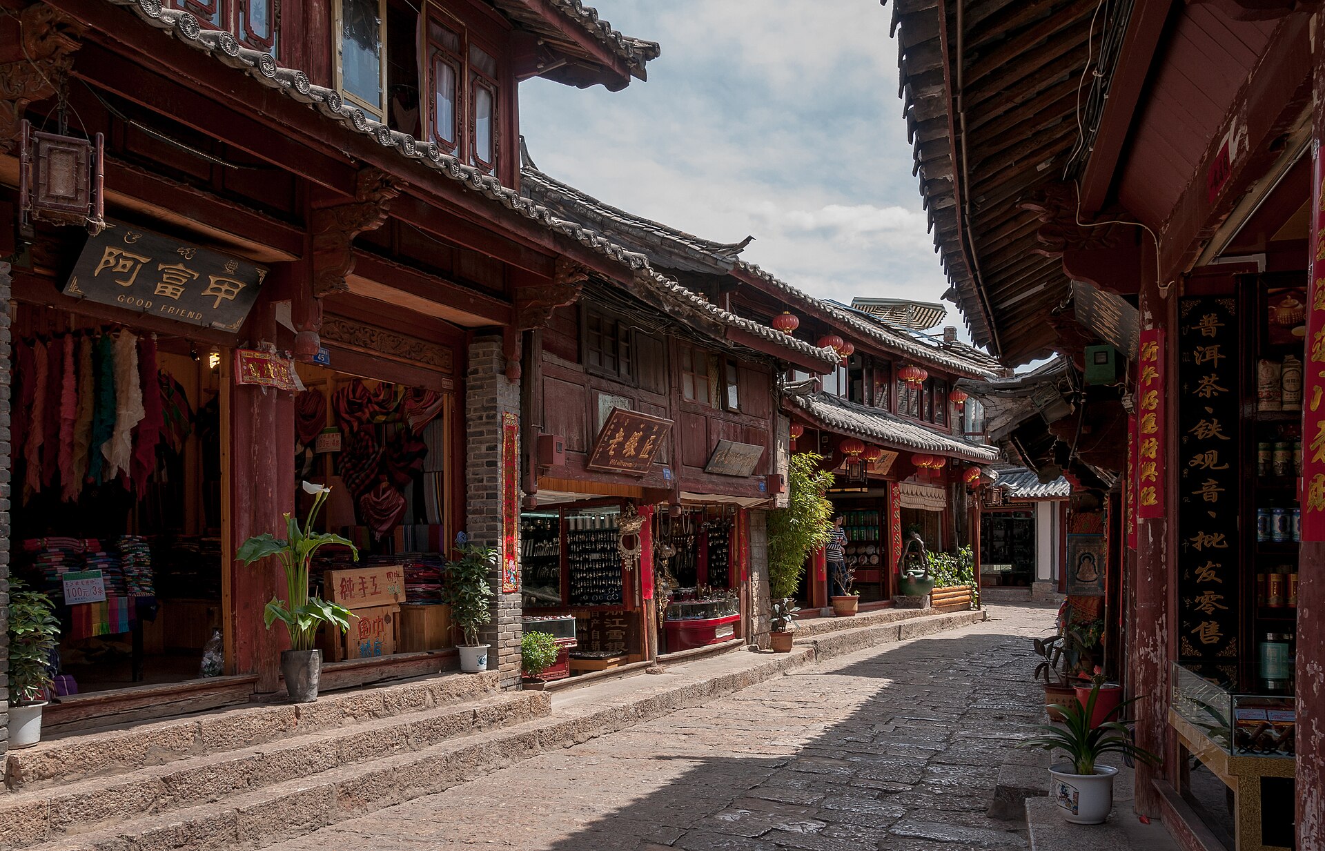 丽江古城的街巷：石板路两侧木构老屋挂着红灯笼，晨光落在招牌与盆栽上